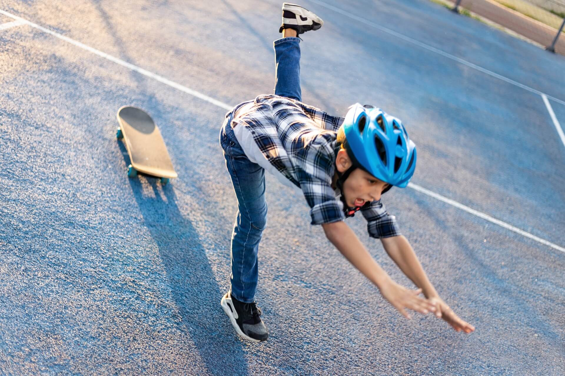 kleines Kind auf Skateboard fällt auf die Straße