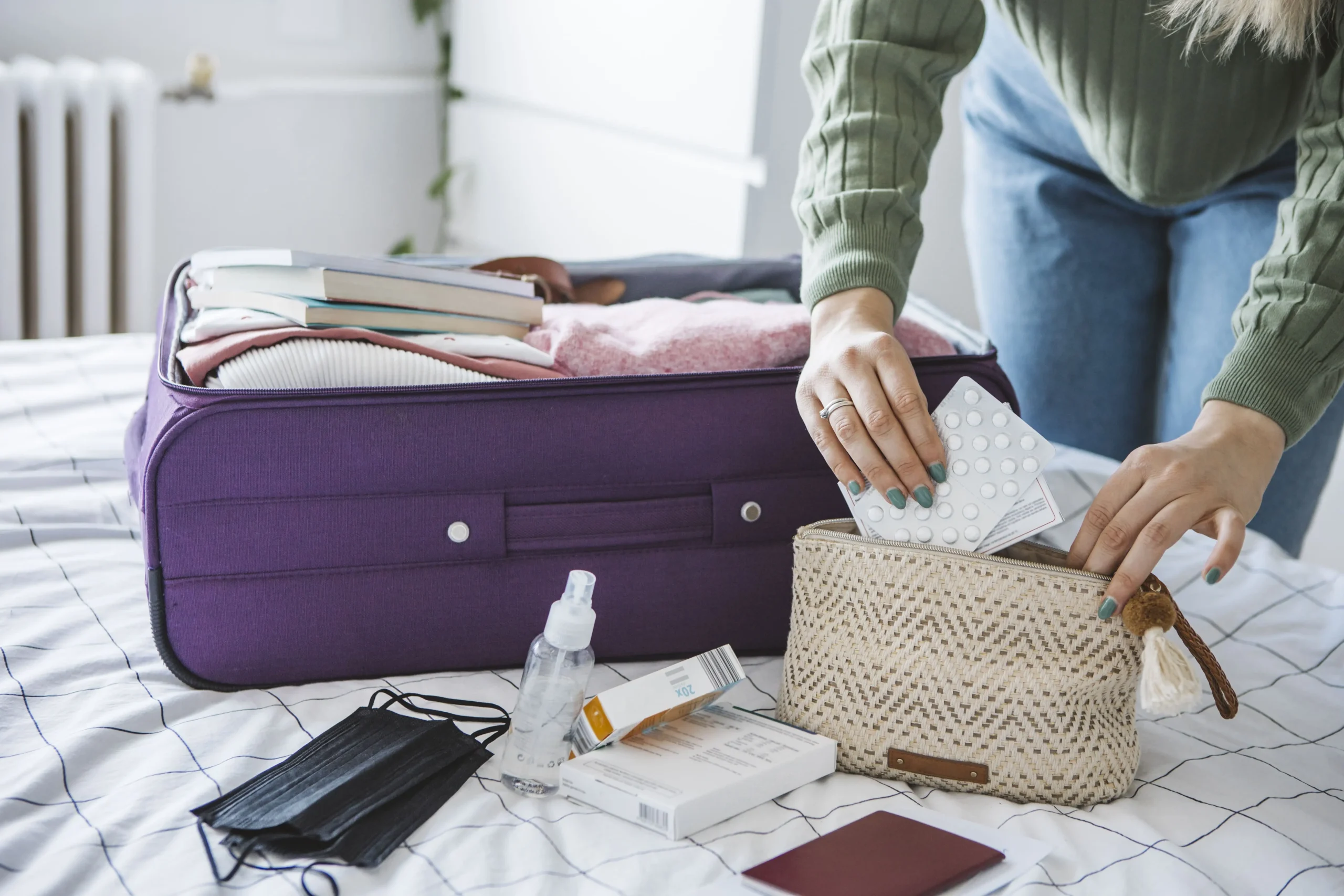 Frau beim Kofferpacken: Eine Reiseapotheke sollte im Urlaub immer dabei sein