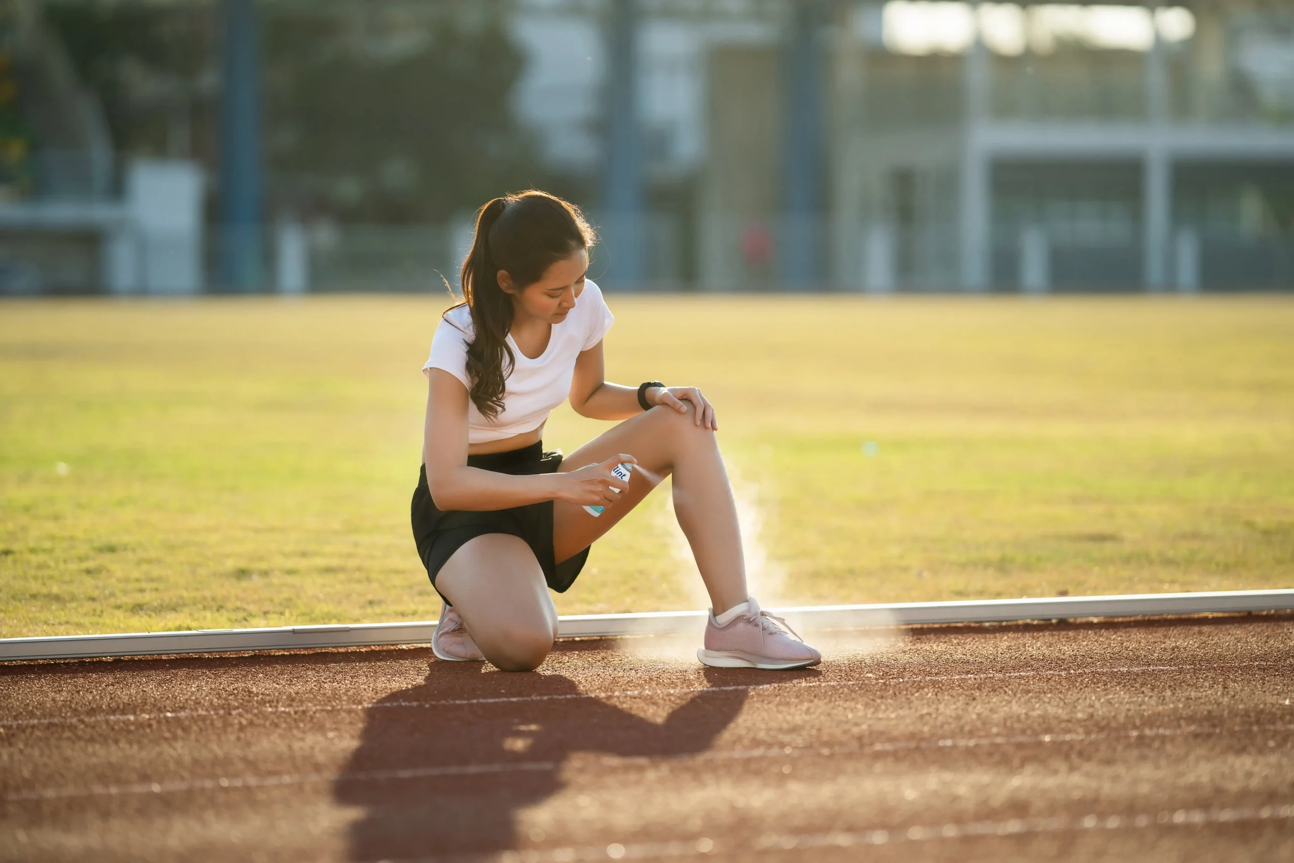 shutterstock_1663967299-bearbeitet-mit-Eis-Spray-v2-min Junge Frau auf dem Sportplatz wendet das flint Med Eis Spray Akut an