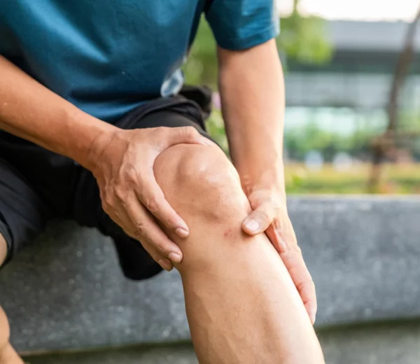 Mann sitzt auf einem Stein und hält sich sein Knie.